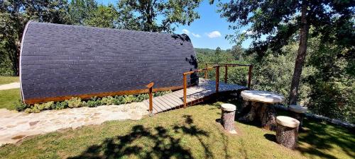 una casa con techo negro y terraza de madera en Green Paradise Glamping, en Covas