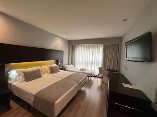 ein Hotelzimmer mit einem großen Bett und einem Flachbild-TV in der Unterkunft Hotel Tent Granada in Granada