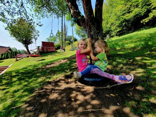 two little girls sitting on a tree swing at Penzion U Sovy in Dolný Kubín