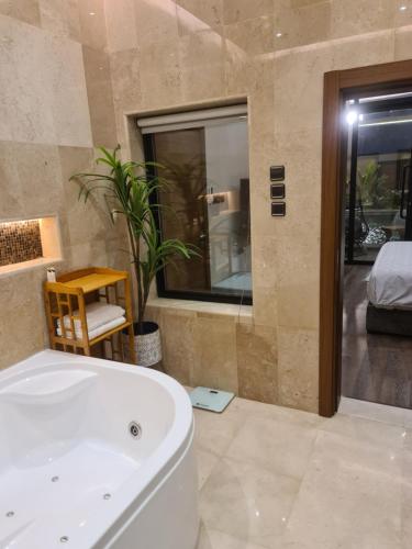 a bathroom with a white tub and a bedroom at Villa Bali Jeddah in Jeddah