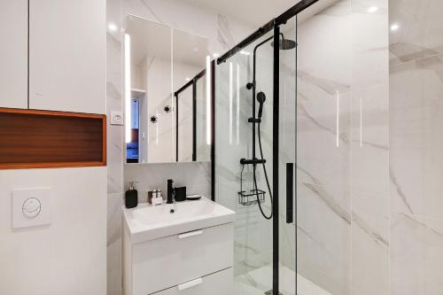 La salle de bains blanche est pourvue d'un lavabo et d'une douche. dans l'établissement CMG - Magnifique appartement-Saint-Germain/Bon marché - Paris 7eme, à Paris