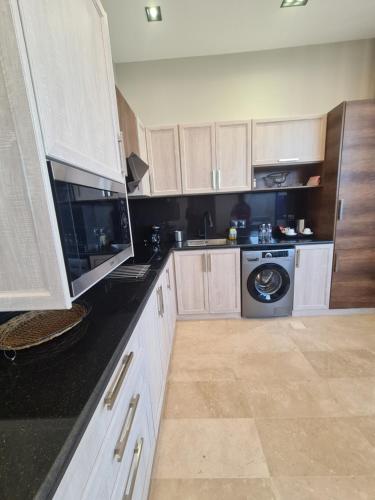 a kitchen with white cabinets and a washing machine at Villa Bali Jeddah in Jeddah