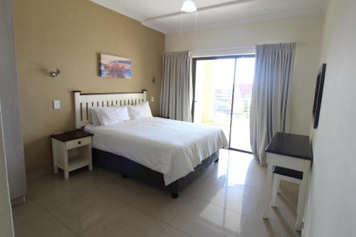 een slaapkamer met een bed, een raam en een bureau bij Saints View Resort Unit 8 in Uvongo Beach