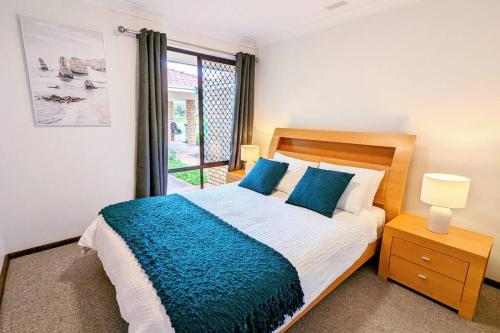 1 dormitorio con 1 cama con manta azul y ventana en Relaxing Home Close to Nature en Bunbury
