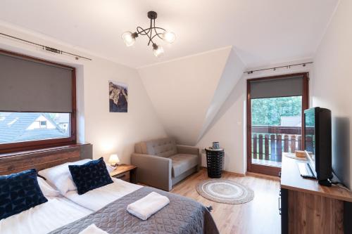 a bedroom with a bed and a flat screen tv at Apartamenty Rodzinne ApartZakop in Zakopane