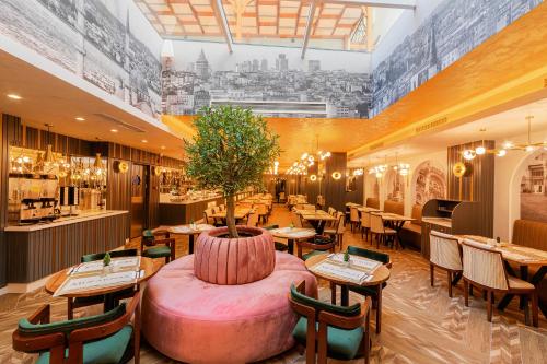 a restaurant with tables and chairs and a tree in a pot at Mukarnas Pera Hotel in Istanbul