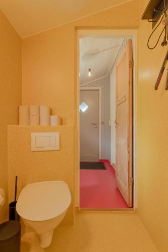 a bathroom with a toilet and a door to a hallway at Cozy 2-bedroom house with a fantastic view in Leynar