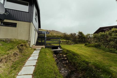 a house with a staircase next to a grass field at Cozy 2-bedroom house with a fantastic view in Leynar