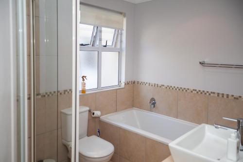 a bathroom with a tub and a toilet and a sink at Kingswood Gardens No. 4 in George