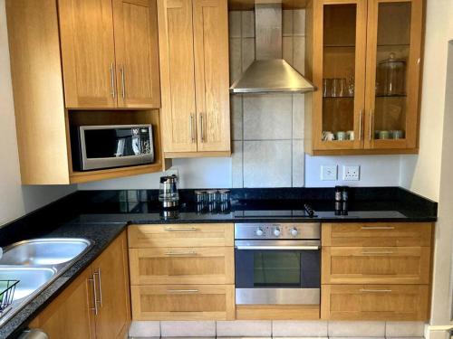 a kitchen with wooden cabinets and a sink and a microwave at Kingswood Gardens No. 4 in George