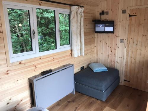 a room with a tv and a ottoman in a cabin at luxury railway carriage with stunning views in Hereford
