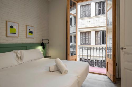 sypialnia z białym łóżkiem i dużym oknem w obiekcie Aspasios Gracia Apartments w Barcelonie