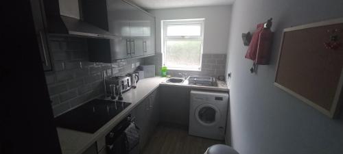 una pequeña cocina con lavadora y lavadora en 6-min Walk to New Cross Parking Long Stay Discounts en Fallings Park