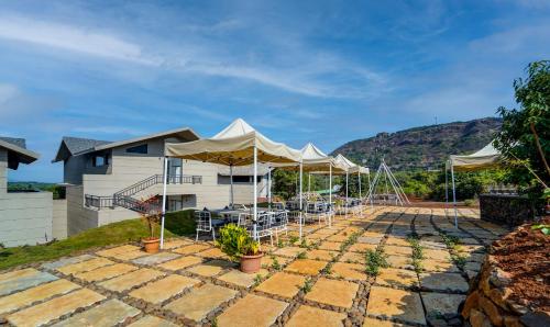 a house with a patio with chairs and umbrellas at Vee Resort- The Suites of Royals in Mahabaleshwar