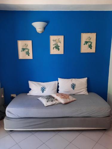 ein Schlafzimmer mit einer blauen Wand und einem Bett mit Kissen in der Unterkunft Casa Antonietta in Ischia
