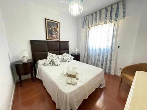 1 dormitorio con 1 cama con sábanas blancas y mesa en PRECIOSO APARTAMENTO VISTAS LATERALES AL MAR, en Isla Canela