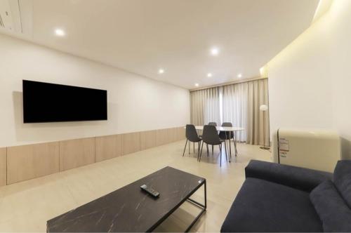 a living room with a couch and a tv on a wall at Geoje Mongdol Beach H Avenue Hotel in Geoje 