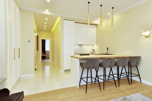 a kitchen with white cabinets and bar stools at Luxury Central Apartment in Putvinskio street in Kaunas