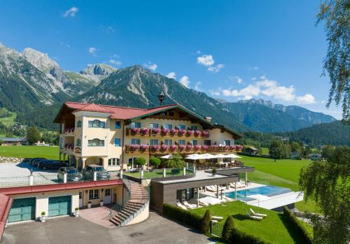 a hotel with a pool and mountains in the background at Hotel Ennstalerhof in Ramsau am Dachstein