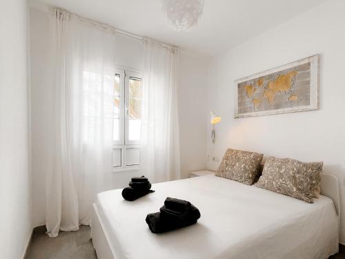 a white bedroom with a bed with two black bags on it at Apartamento Maëlle Playa Blanca in Playa Blanca
