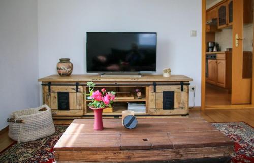uma sala de estar com televisão e um vaso com flores em Ferienwohnung Erzgebirgsblick em Thermalbad Wiesenbad