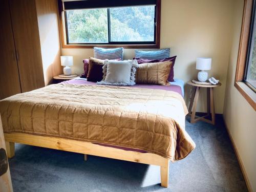 1 dormitorio con 1 cama grande con almohadas y ventana en Red ceder cottage - Great ocean road - Port Campbell, en Port Campbell