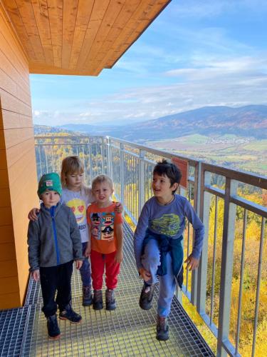 three children are standing on a balcony of a mountain at Chata Polomka s Jacuzzi - Vidíte deti na dvore z obývačky - Pri potoku - Výhľad na Polomské Očko in Brezno
