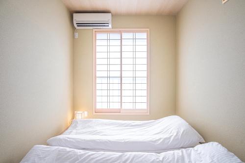 a bedroom with a white bed and a window at Bungetsu Shokaku Kaikan in Kyoto