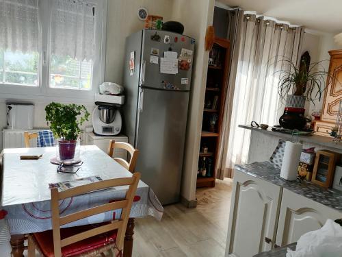 a kitchen with a stainless steel refrigerator and a table at Maison proche circuit 24h du mans in Spay