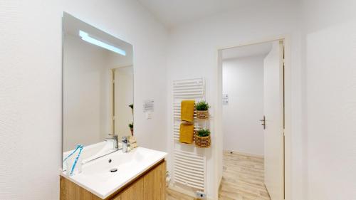 La salle de bains est pourvue d'un lavabo et d'un miroir. dans l'établissement Résidence SWEETLY Saint Augustin, à Bordeaux
