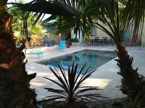 una piscina con palmeras, mesa y sillas en Petit studio au calme, en La Crau