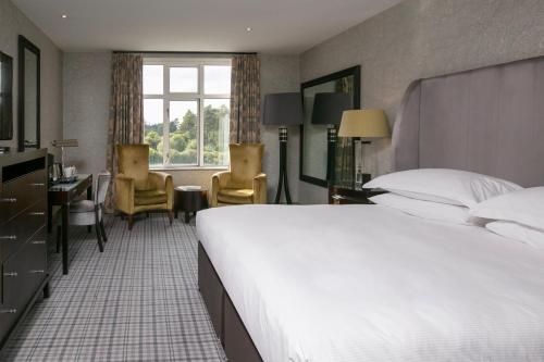 um quarto de hotel com uma cama grande e uma secretária em Slaley Hall Hotel, Spa & Golf Resort em Slaley