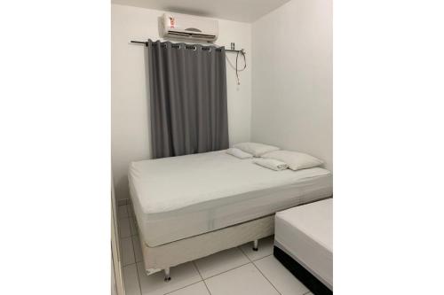 um pequeno quarto com uma cama e uma cortina em Condomínio Portal de Maragogi- Flats duplex super aconchegantes e confortáveis em Maragogi