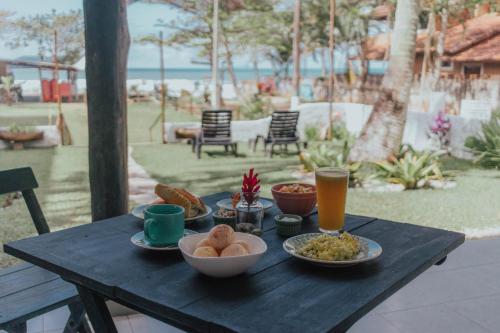 ein schwarzer Tisch mit Teller mit Speisen und Getränken darauf in der Unterkunft Yabás Praia in Ubatuba