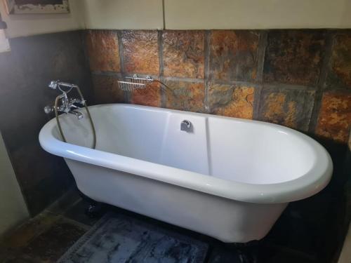 a white bath tub in a bathroom with a tile wall at Point Village Accommodation -Linky's House in Mossel Bay