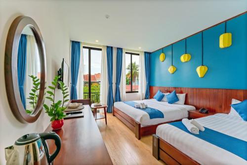 Habitación de hotel con 2 camas y espejo en Saclo Villa and Hostel, en Hoi An
