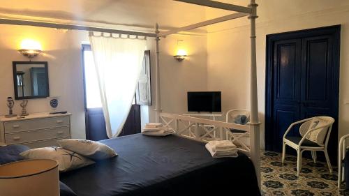 a bedroom with a bed and a desk and a television at La Villa Rossa in Santa Marina Salina