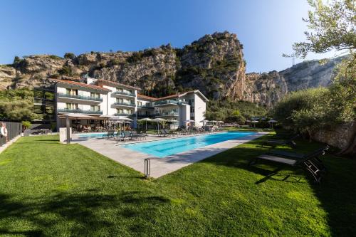 a resort with a pool with a mountain in the background at Aktivhotel Santalucia in Nago-Torbole