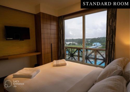 a bedroom with a bed and a large window at BayLeaf Inn in Port Blair