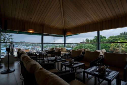 - un restaurant avec des canapés, des tables et de grandes fenêtres dans l'établissement BayLeaf Inn, à Port Blair