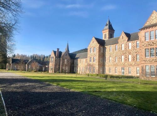 a large brick building with a grass field in front of it at Great Glen Townhouse Inverness in Inverness