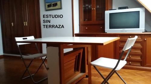 Habitación con escritorio con 2 sillas y TV. en Rua Granxas, n 13, Piso con terraza o Estudio sin terraza, en Viveiro