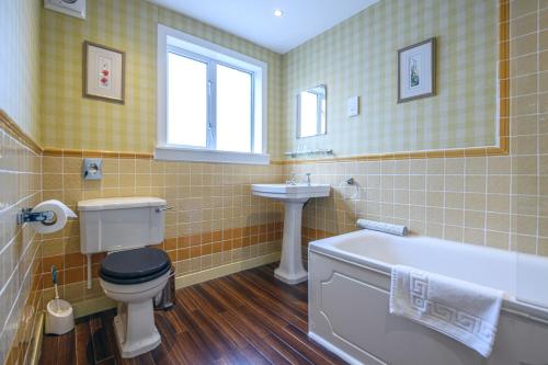 a bathroom with a tub and a toilet and a sink at The Portland Hotel in Lybster