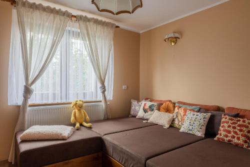 a couch with a teddy bear sitting on it in front of a window at Cyprysovnia in Gnieżdżewo