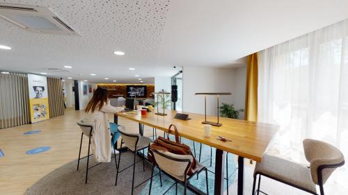 Une femme debout à une longue table dans un bureau dans l'établissement Résidence SWEETLY Saint Augustin, à Bordeaux