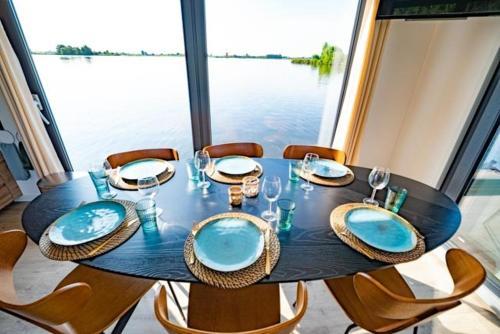 mesa de comedor con sillas y mesa con platos azules en Surla luxury sailing Houseboat Splendid at Marina Monnickendam, en Monnickendam