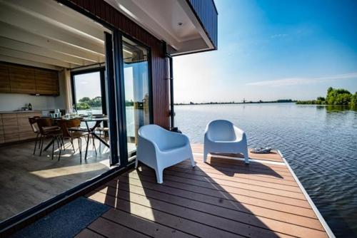 a house with two chairs and a table and water at Surla luxury sailing Houseboat Splendid at Marina Monnickendam in Monnickendam