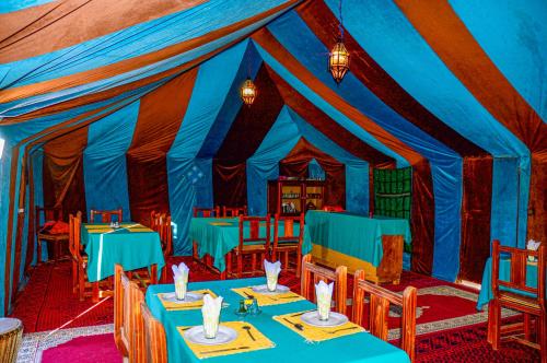 a blue and red tent with tables and chairs at Les Roches Desert Camp in Merzouga