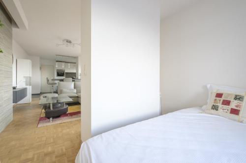 1 dormitorio con 1 cama blanca y sala de estar en Nice studio with big terrace en Bruselas