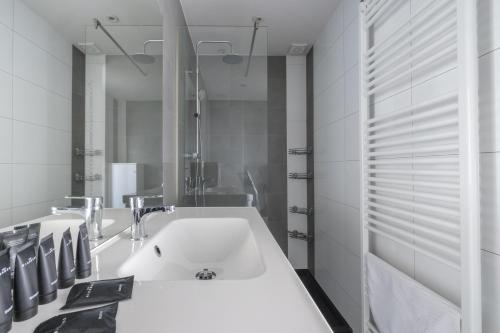 a white bathroom with a sink and a mirror at Nice studio with big terrace in Brussels